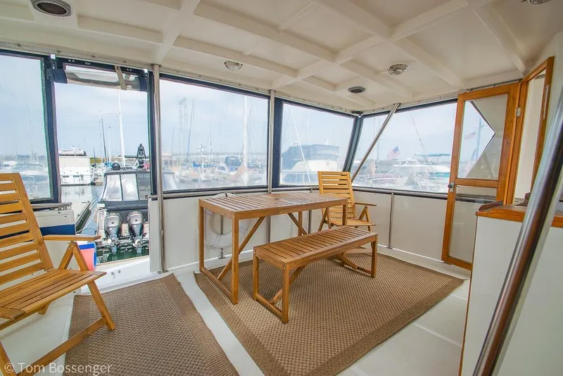 Slide: The Image of Enclosed deck of 1986 Ponderosa 47 yacht with wooden furniture and marina view. - 36