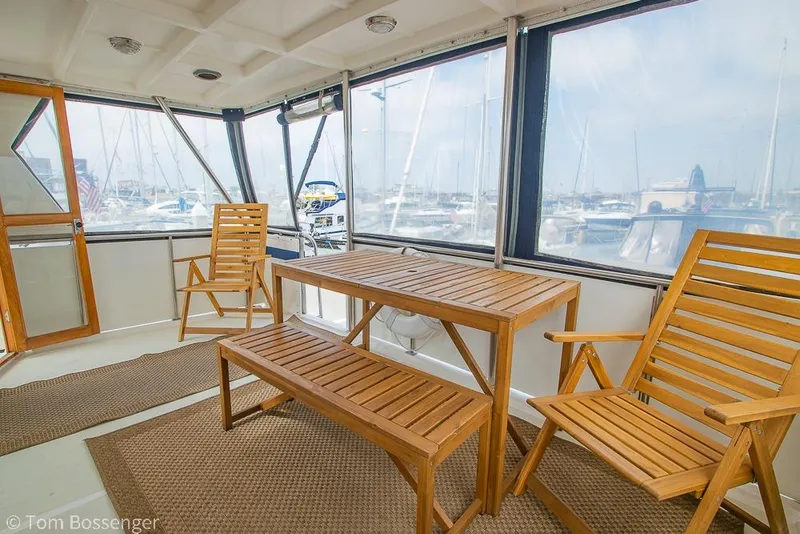 Slide: The Image of Enclosed deck of 1986 Ponderosa 47 yacht with wooden furniture and marina view. - 37
