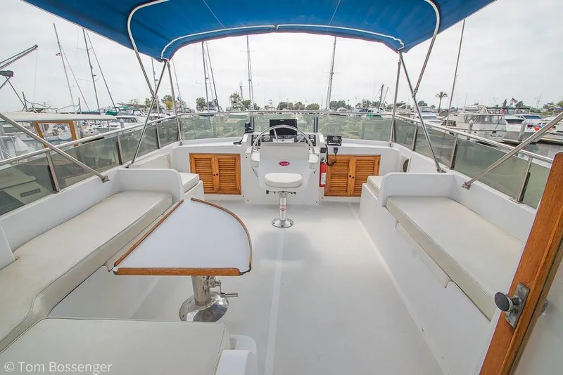 Slide: The Image of 1986 Ponderosa 47 yacht cockpit with blue canopy, seating, and steering wheel in marina. - 44