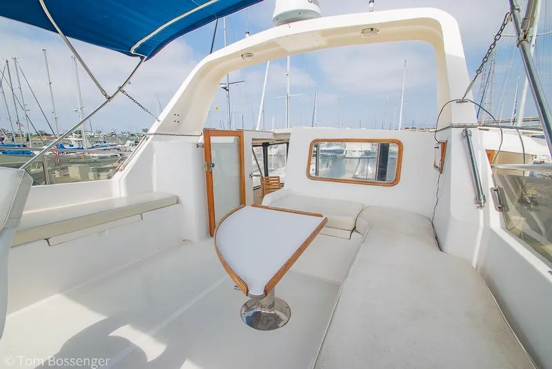 Slide: The Image of 1986 Ponderosa 47 yacht deck with seating and table, marina background. - 47