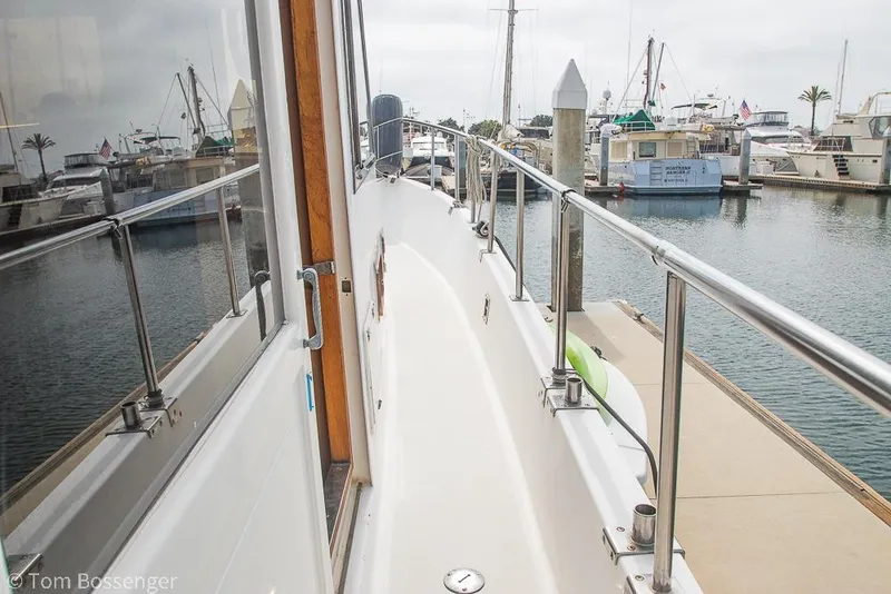 Slide: The Image of 1986 Ponderosa 47 yacht docked at marina, showcasing sleek deck and railing. - 61