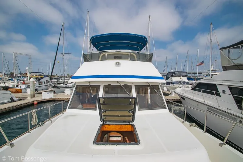 Slide: The Image of 1986 Ponderosa 47 yacht docked at marina, surrounded by other boats under a blue sky. - 65