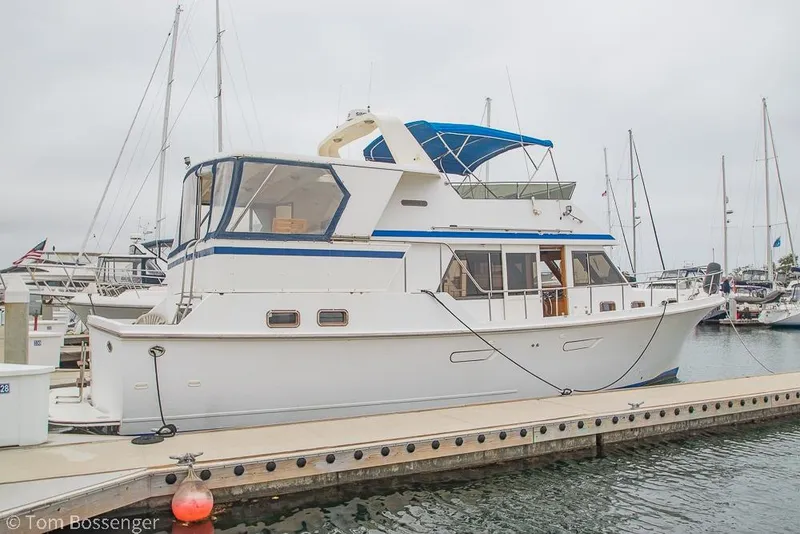 Slide: The Image of 1986 Ponderosa 47 yacht docked at marina, featuring blue accents and spacious deck. - 81