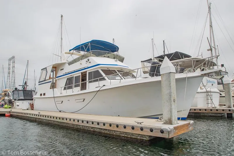Slide: The Image of 1986 Ponderosa 47 yacht docked at marina, featuring blue accents and spacious deck. - 82