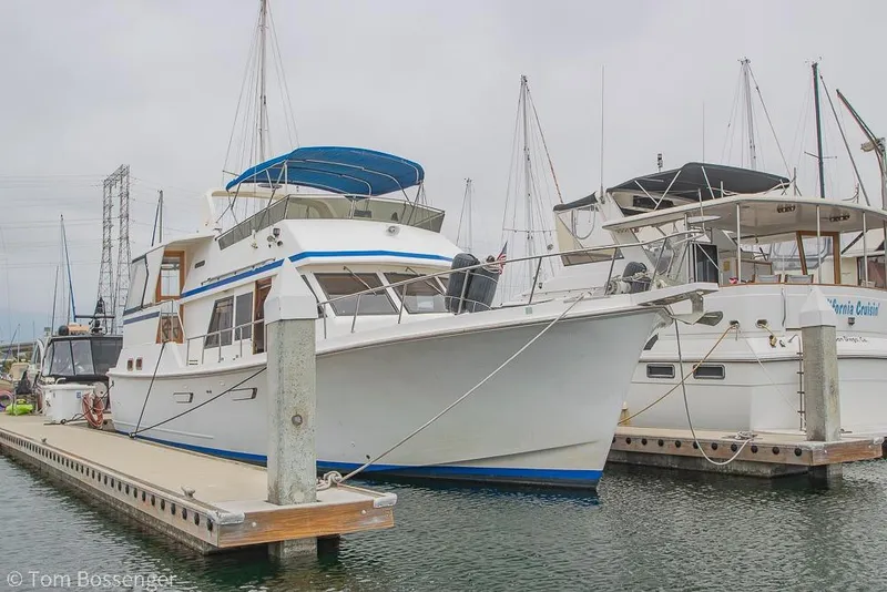 Slide: The Image of 1986 Ponderosa 47 yacht docked at marina, featuring blue accents and spacious deck. - 86