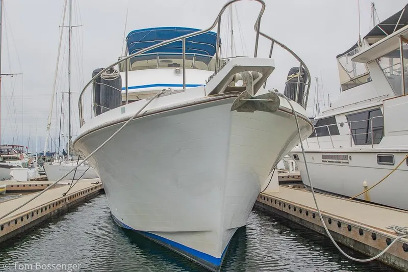 Slide: The Image of 1986 Ponderosa 47 yacht docked at marina, front view with blue canopy. - 87