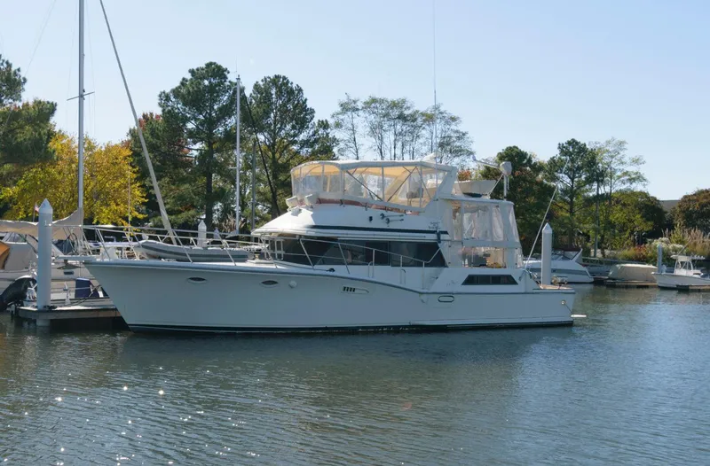 The Image of 1988 Symbol 55 Cockpit Motor Yacht docked in a serene marina setting. - 0