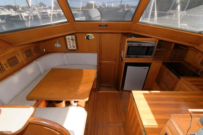 Slide: The Image of 1988 Symbol 55 Cockpit Motor Yacht interior with dining area, kitchenette, and wood finishes. - 15