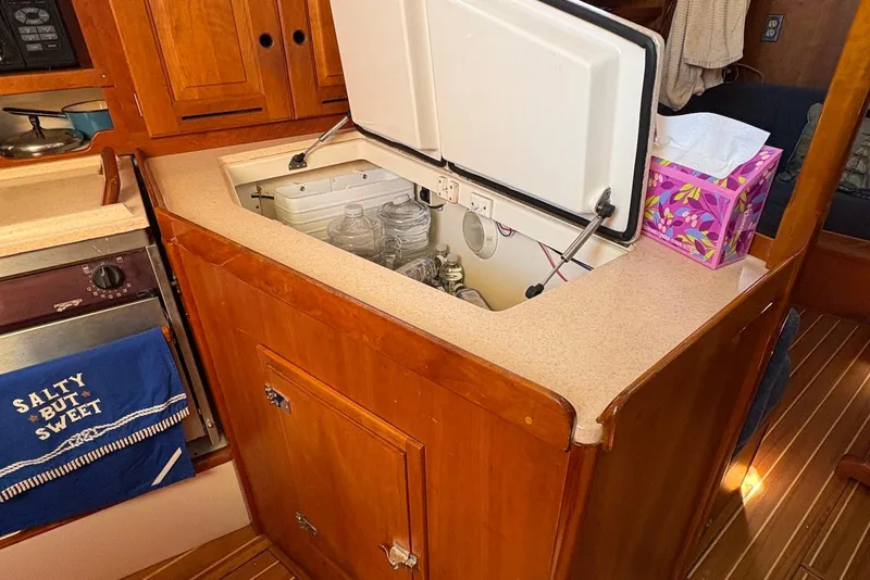 Slide: The Image of 2005 Tartan 4100 yacht galley with open storage, wooden cabinetry, and nautical decor. - 13