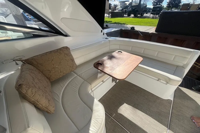 Slide: The Image of 2009 Cobalt 373 boat interior with white seating, wooden table, and decorative cushions. - 13