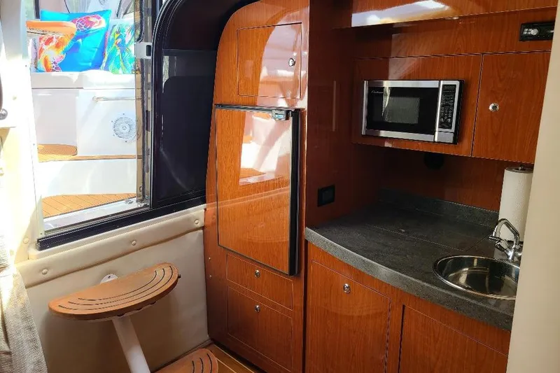 Slide: The Image of 2009 Regal Commodore 3760 IB yacht interior with kitchenette, featuring wood cabinetry and modern appliances. - 16
