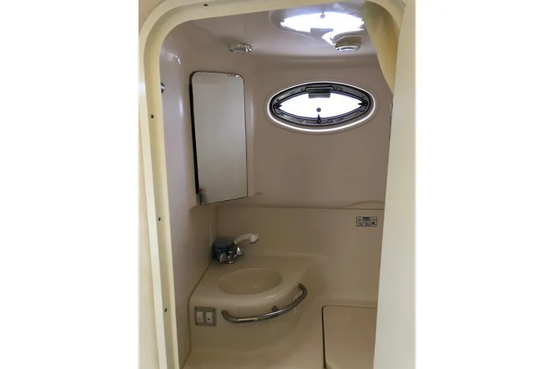 Slide: The Image of 2001 Sea Ray 290 Sundancer bathroom with sink, mirror, and porthole window. - 15