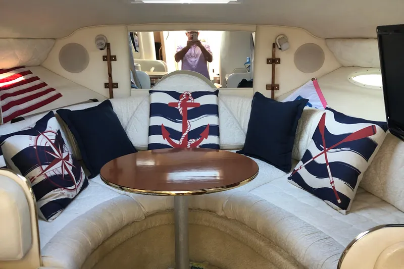 Slide: The Image of Interior of 2001 Sea Ray 290 Sundancer with nautical-themed cushions and round table. - 4