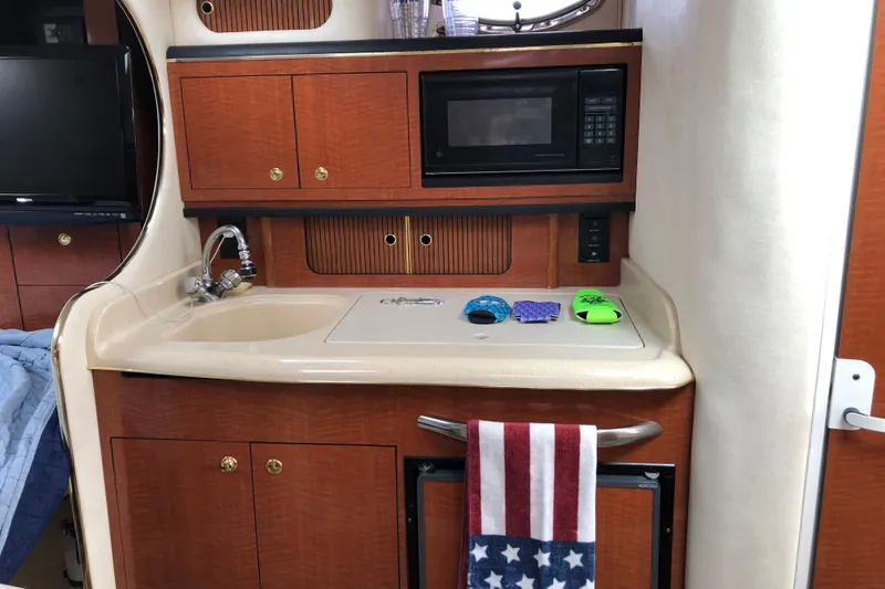 Slide: The Image of 2001 Sea Ray 290 Sundancer cabin kitchen with sink, microwave, and American flag towel. - 9