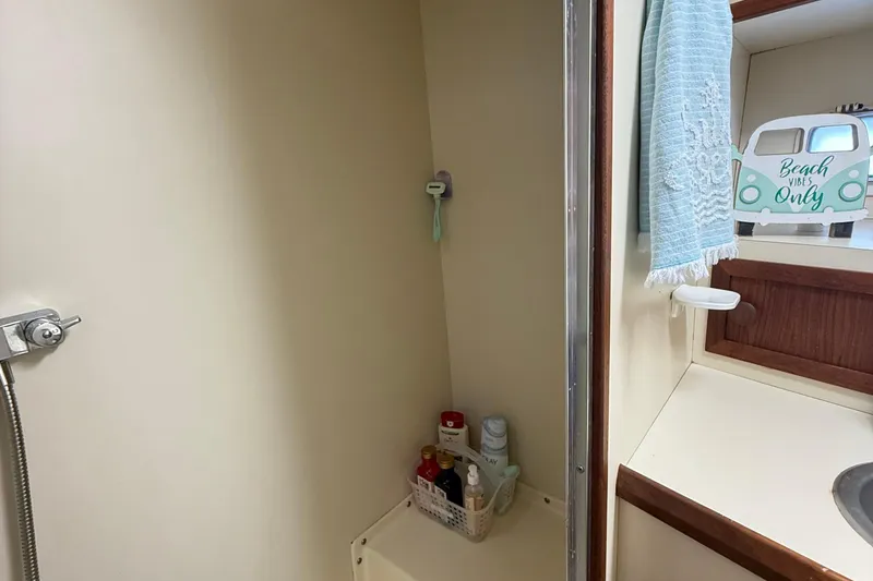 Slide: The Image of 1987 Chris-Craft 392 Commander bathroom with shower, toiletries, and beach-themed decor. - 13