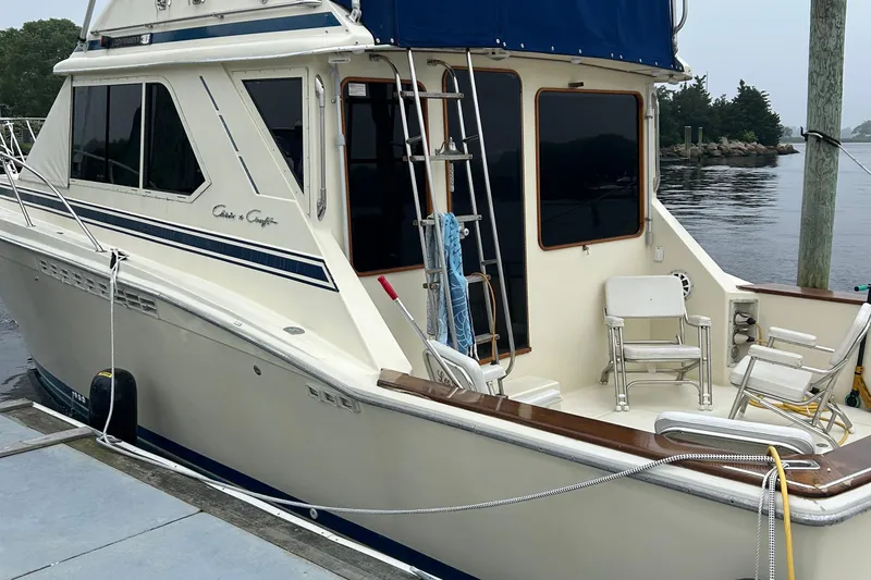 Slide: The Image of 1987 Chris-Craft 392 Commander yacht docked by the water, featuring a spacious deck area. - 3