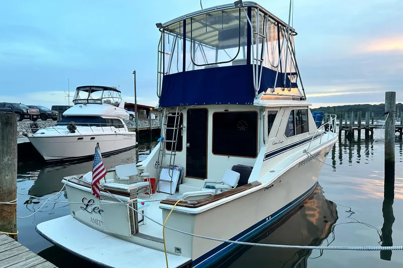 Slide: The Image of 1987 Chris-Craft 392 Commander yacht docked at sunset, featuring a blue canopy. - 7