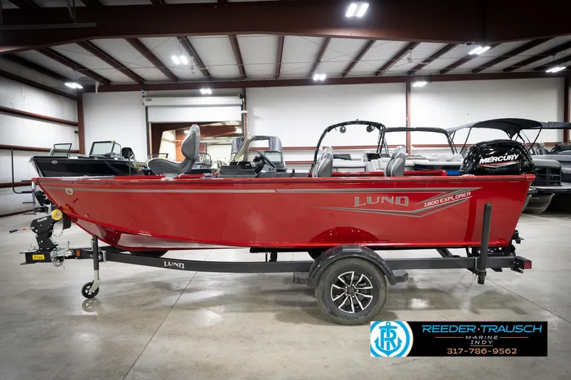 Slide: The Image of 2026 Lund 1800 Explorer Sport boat in a showroom, featuring a red exterior and Mercury engine. - 10