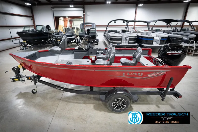 The Image of 2026 Lund 1800 Explorer Sport boat in showroom, featuring red exterior and Mercury engine. - 2