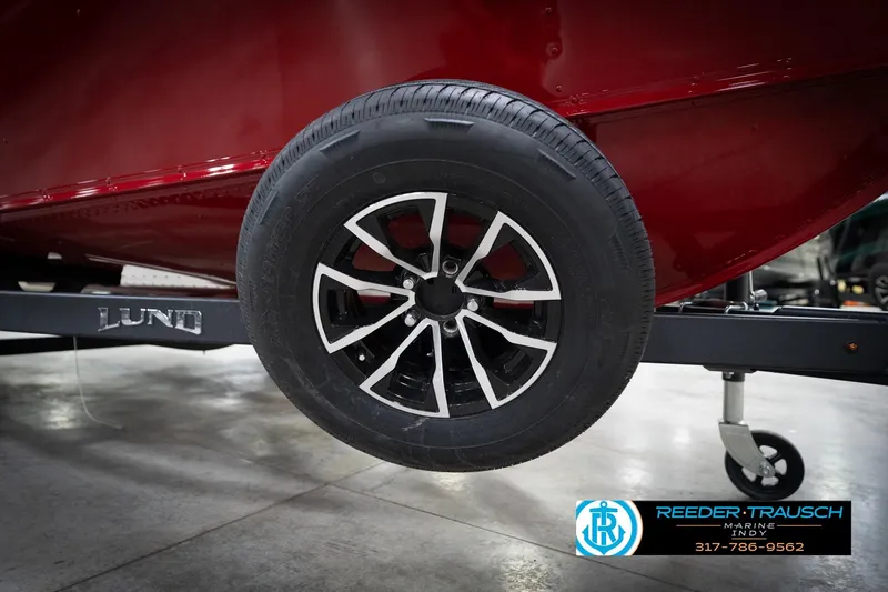 Slide: The Image of 2026 Lund 1800 Explorer Sport trailer wheel, black and silver design, in a showroom setting. - 50