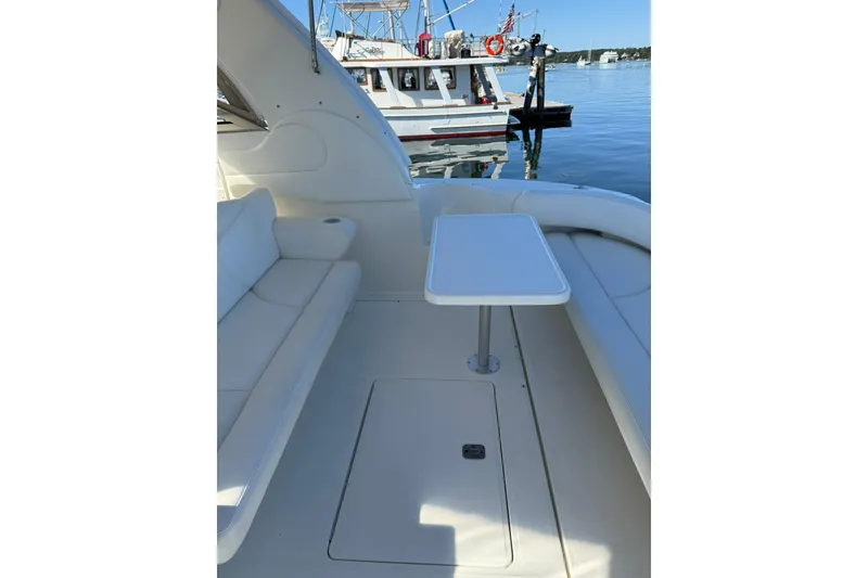 Slide: The Image of 2000 Sea Ray 410 Express Cruiser interior with seating and table, docked by the water. - 13