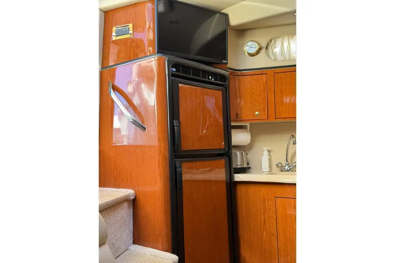 Slide: The Image of 2000 Sea Ray 410 Express Cruiser interior with wood cabinetry and kitchenette. - 44