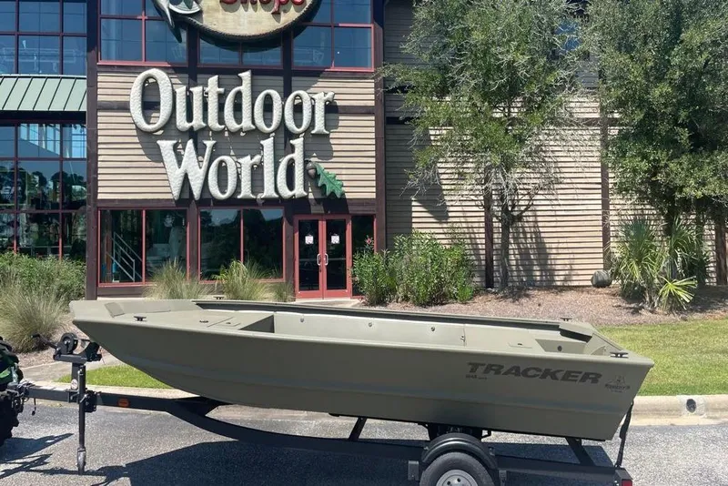 Slide: The Image of 2026 Tracker Grizzly 1648 Utility boat on trailer outside Outdoor World store. - 6