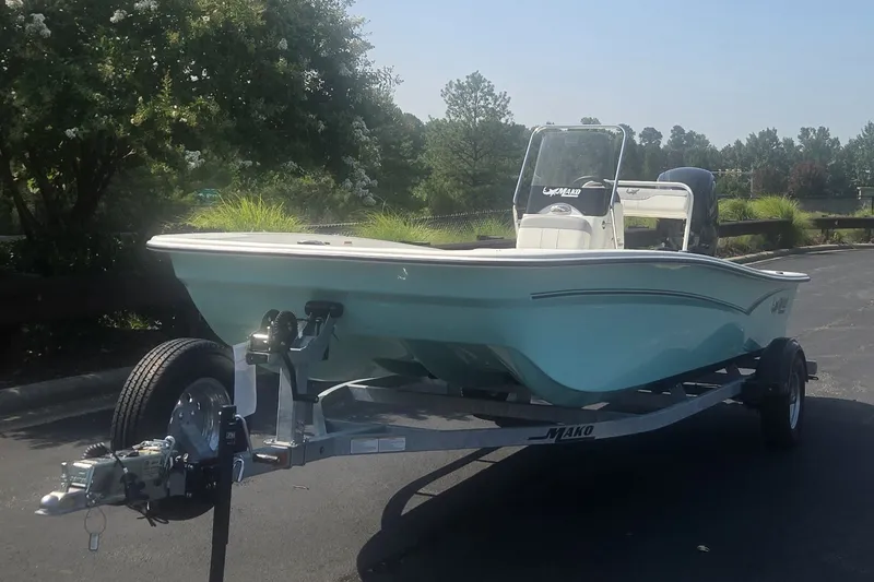 Slide: The Image of 2026 Mako Pro Skiff 17 CC boat on trailer, parked outdoors, surrounded by greenery. - 1