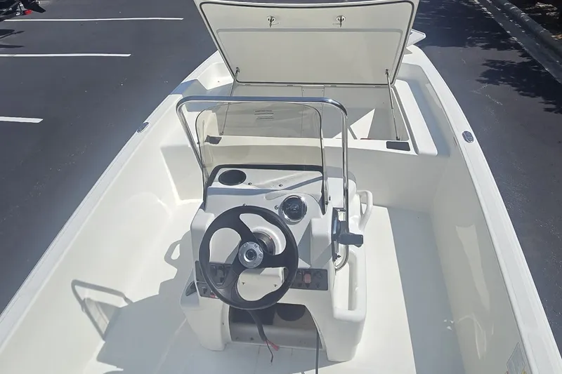 Slide: The Image of 2026 Mako Pro Skiff 17 CC boat interior with steering console and open storage compartment. - 2