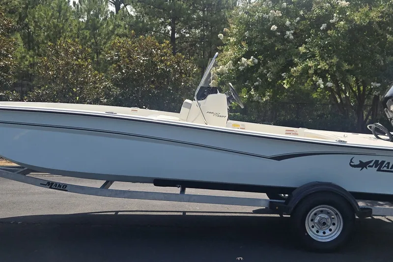 The Image of 2026 Mako Pro Skiff 17 CC boat on trailer, surrounded by trees. - 0