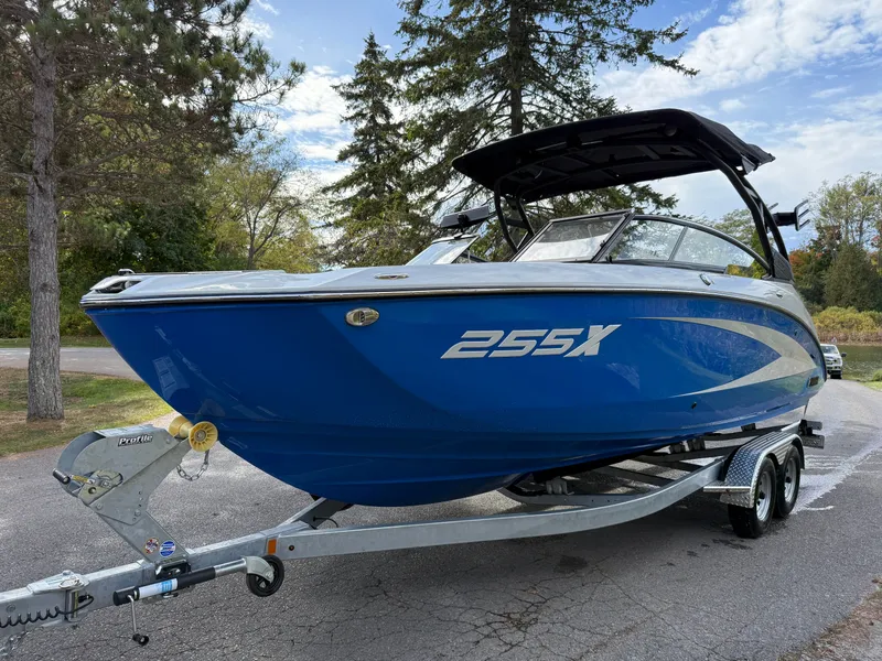 Slide: The Image of 2025 Yamaha Boats 255 XD in blue on a trailer, parked outdoors. - 30