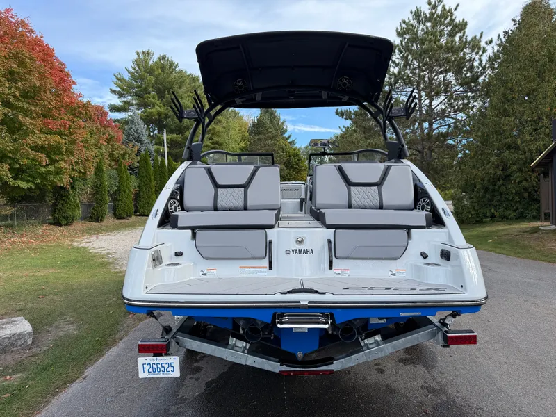 Slide: The Image of 2025 Yamaha Boats 255 XD, rear view, parked on a driveway with trees in the background. - 32