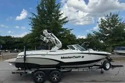 Slide: The Image of 2014 MasterCraft X10 boat on trailer, parked outdoors under a blue sky. - 1