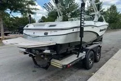 Slide: The Image of 2014 MasterCraft X10 boat on trailer, parked outdoors with trees in the background. - 5