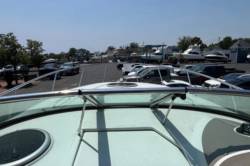 Slide: The Image of 2016 Crownline 264 CR boat docked, surrounded by parked cars and other boats. - 16