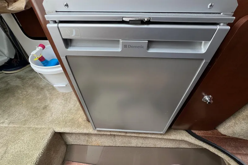 Slide: The Image of 2016 Crownline 264 CR boat interior with Dometic fridge and carpeted flooring. - 19