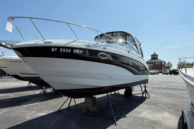 Slide: The Image of 2016 Crownline 264 CR boat on stands in a parking lot under clear sky. - 2
