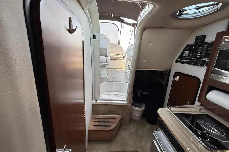 Slide: The Image of Interior view of 2016 Crownline 264 CR boat, featuring cabin amenities and control panel. - 20