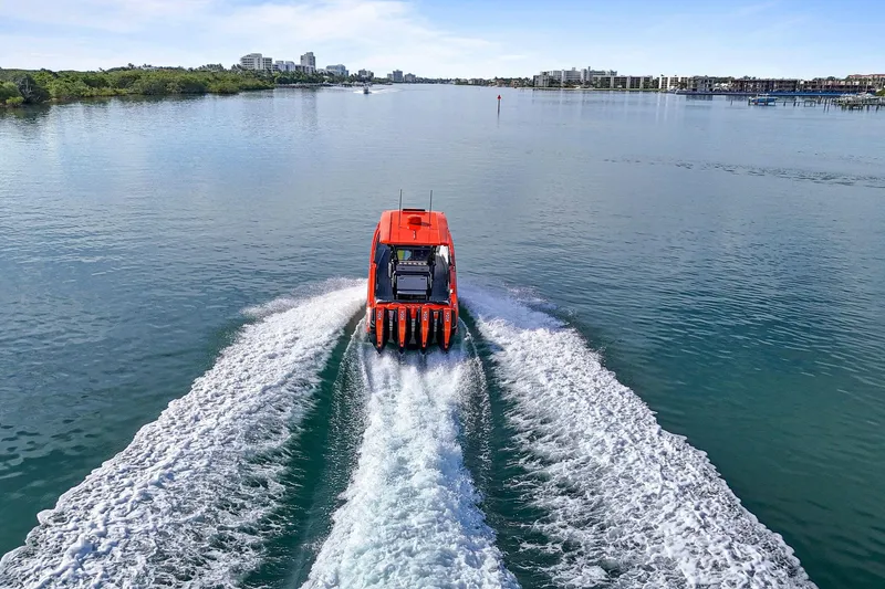 Slide: The Image of 2026 Nor-Tech 390 Sport Center Console cruising on calm waters, cityscape in background. - 22