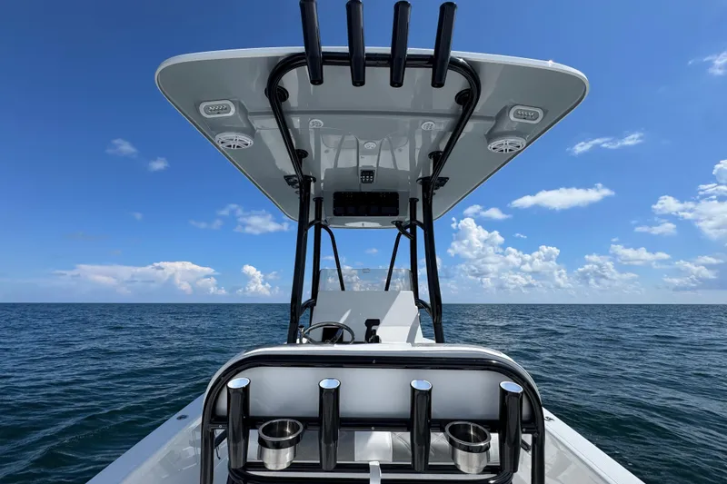 Slide: The Image of 2026 BlackJack 256 Bay boat interior with rod holders and seating, under clear blue sky. - 23