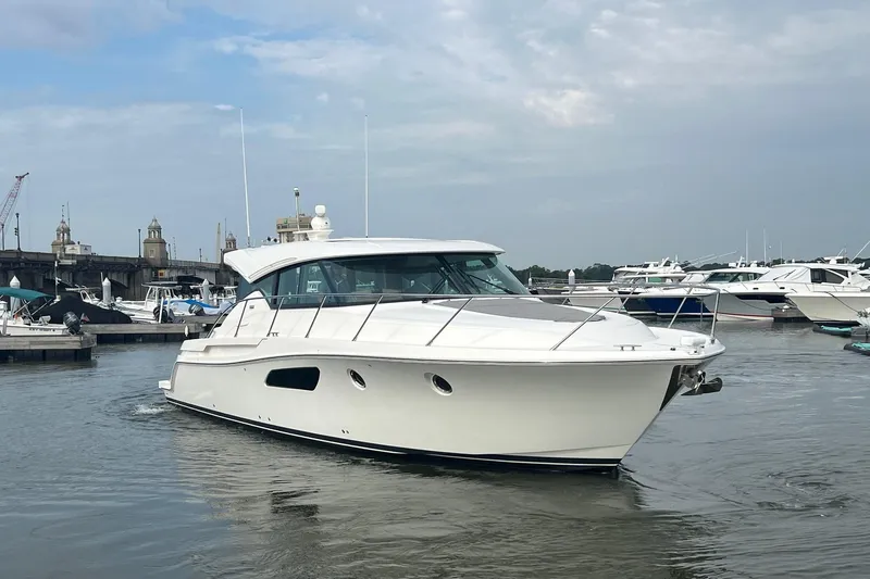 Slide: The Image of 2023 Tiara Yachts C44 Coupe cruising in a marina under a cloudy sky. - 11