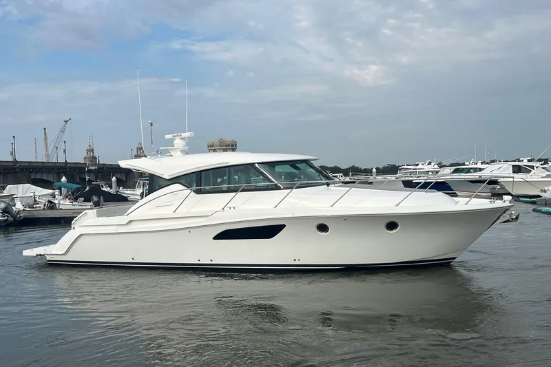Slide: The Image of 2023 Tiara Yachts C44 Coupe in marina, sleek design, calm waters, overcast sky. - 12