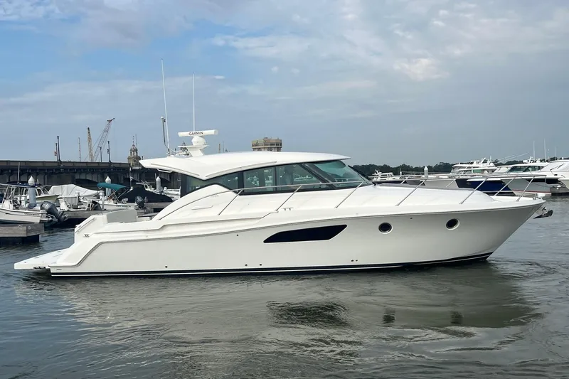 Slide: The Image of 2023 Tiara Yachts C44 Coupe in marina, sleek design, white exterior, calm water. - 13