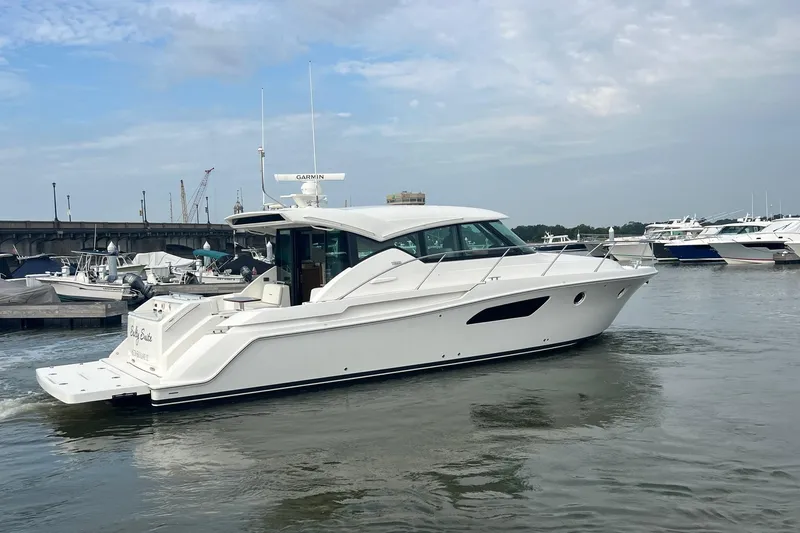 Slide: The Image of 2023 Tiara Yachts C44 Coupe cruising in a marina under a cloudy sky. - 14