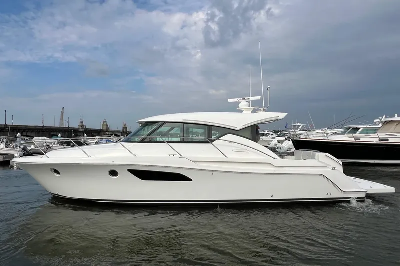 Slide: The Image of 2023 Tiara Yachts C44 Coupe in marina, sleek design, white exterior, calm waters. - 2
