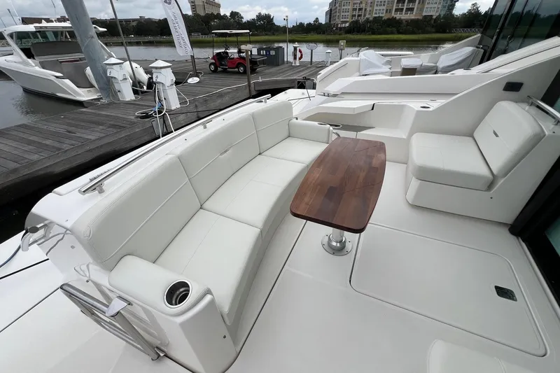Slide: The Image of 2023 Tiara Yachts C44 Coupe, elegant deck seating with wooden table, docked at marina. - 21