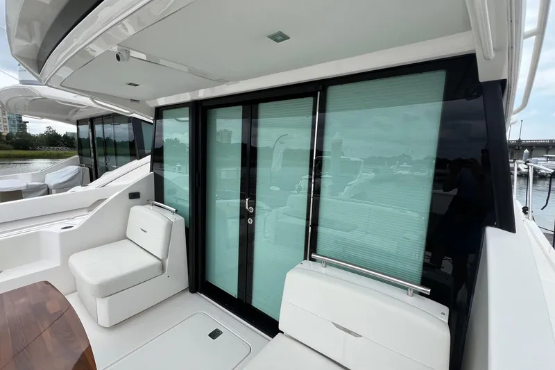 Slide: The Image of 2023 Tiara Yachts C44 Coupe, sleek exterior with glass doors and seating area. - 26