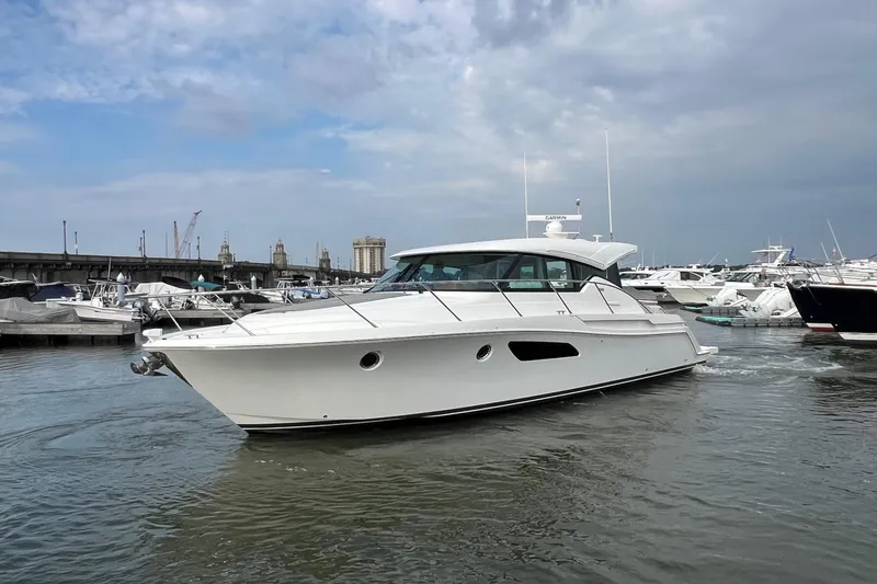 Slide: The Image of 2023 Tiara Yachts C44 Coupe in marina, sleek design, overcast sky. - 4