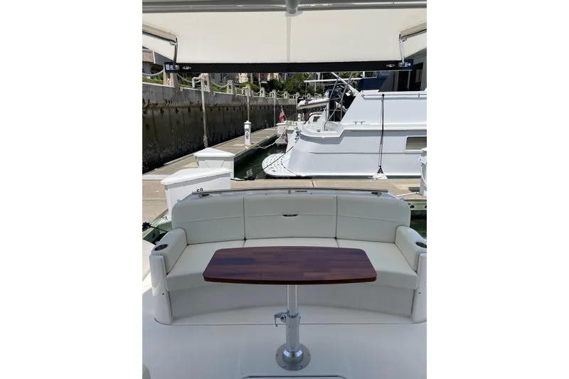 Slide: The Image of 2023 Tiara Yachts C44 Coupe with elegant seating and wooden table in marina setting. - 43