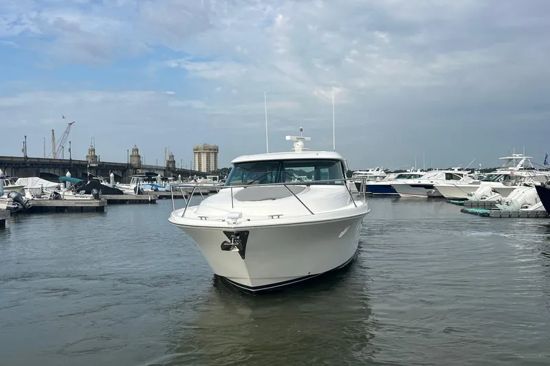 Slide: The Image of 2023 Tiara Yachts C44 Coupe in marina, surrounded by other boats under cloudy sky. - 6